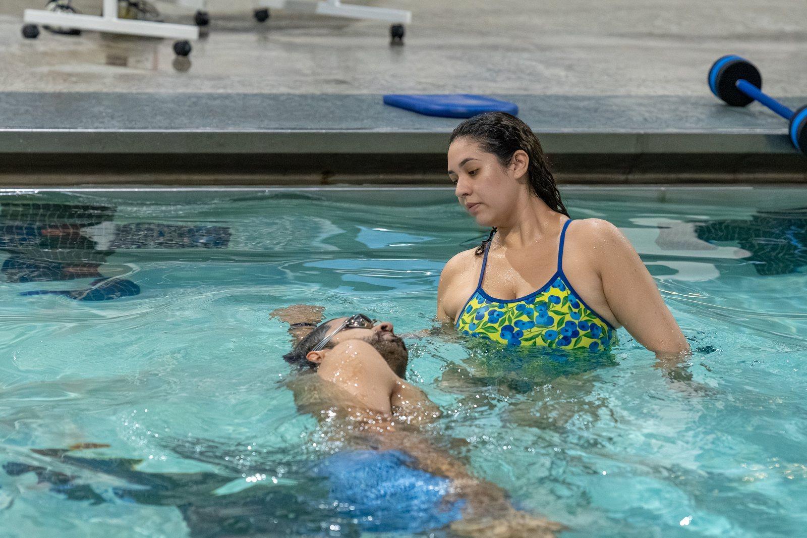 Coach supporting an adult learning to float on their back at Old City Swim School