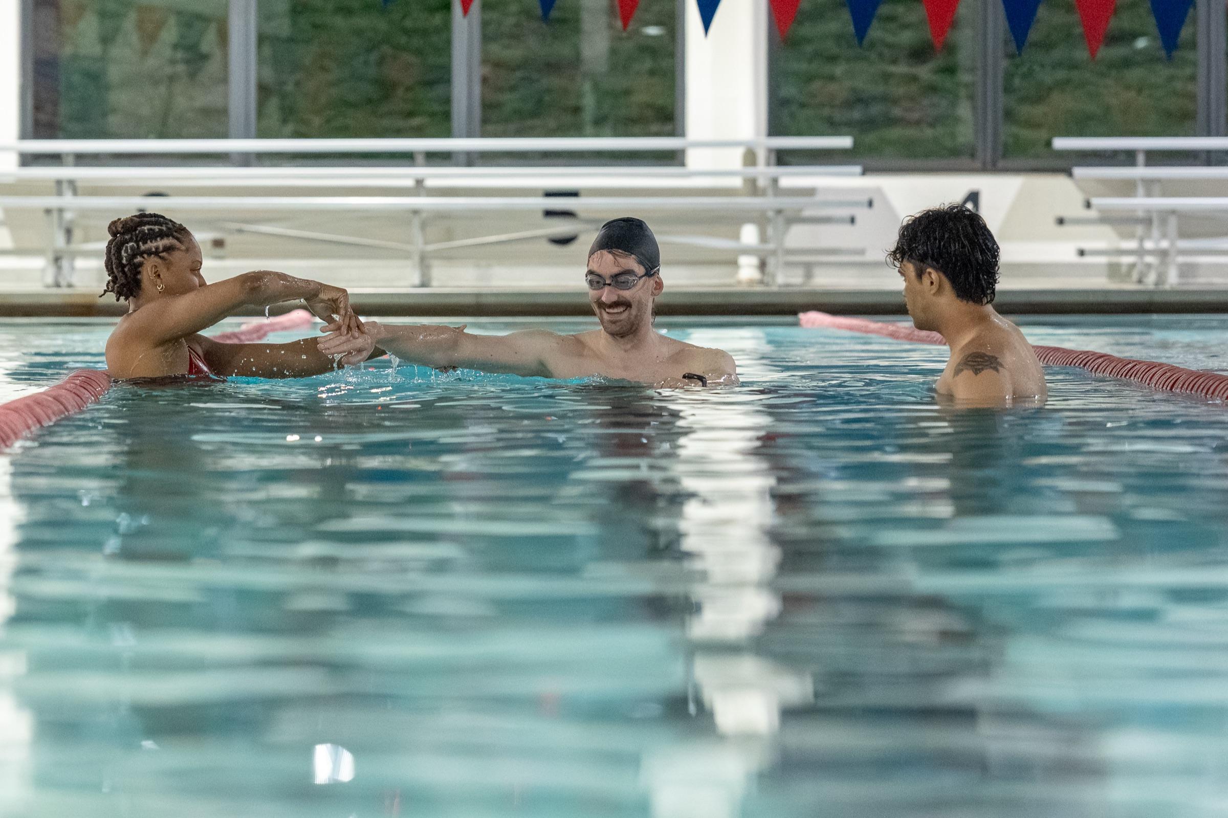 Three adult swimmers celebrating in the pool at Old City Swim School