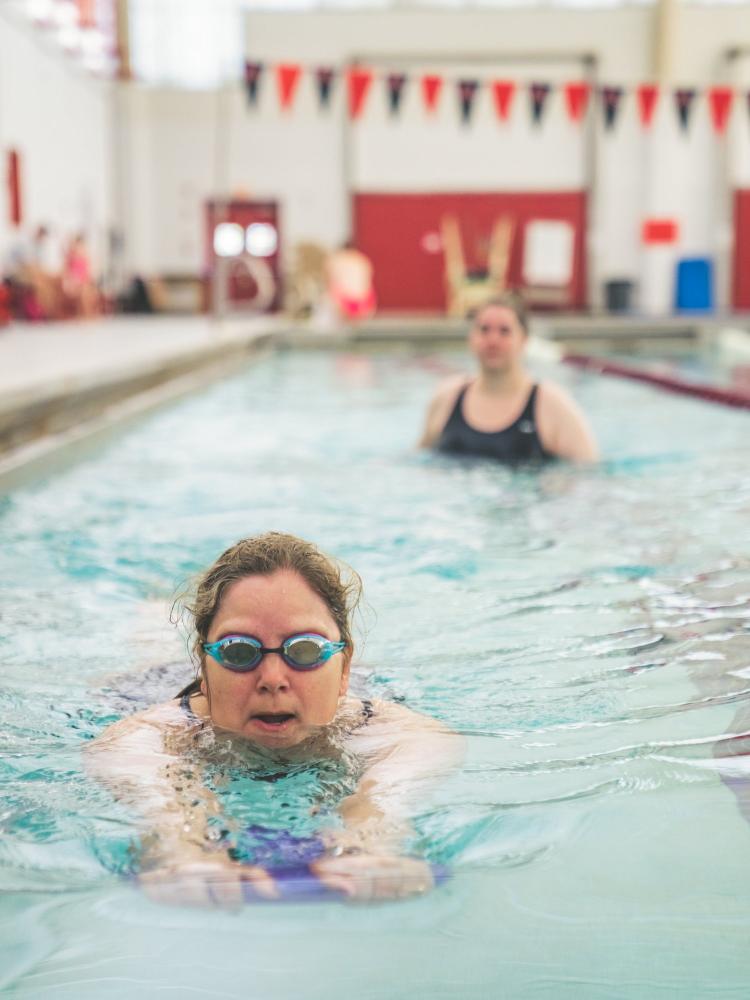 Adult swimmer driving a kickboard down the lane during a drill