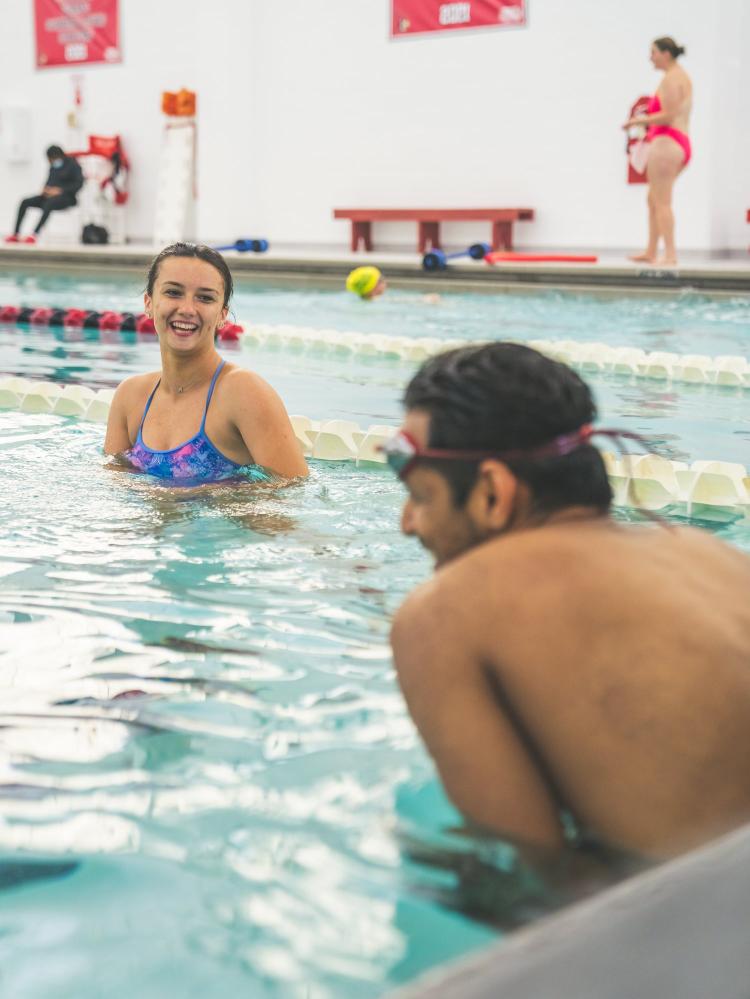 A coach working one-on-one with an adult swimmer at the pool wall
