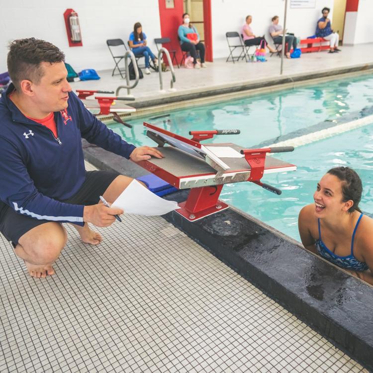 Coach Sean Emery reviewing lesson notes with an adult student at the pool edge